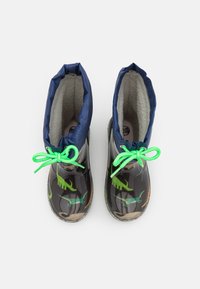 Bottes en caoutchouc avec un motif de dinosaure camouflage, en noir et gris, avec des poignets en tissu bleu et des lacets vert néon. Texture intérieure douce.