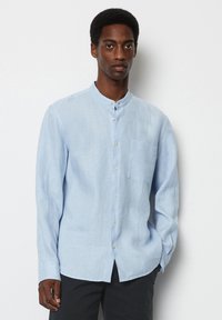 Lichtblauw, langmouwen linnen shirt met een staande kraag, knopen aan de voorkant en een borstzak. Heeft een glad, textuur stof.