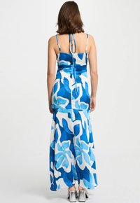 Maxi-jurk met een bloemenpatroon in verschillende tinten blauw en wit, met dunne spaghettibandjes en een vloeiende silhoutte.