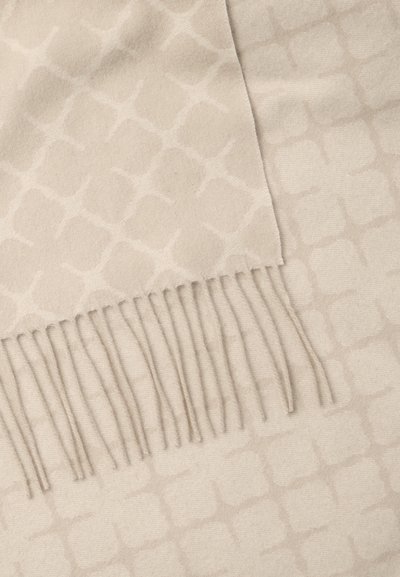 Μπεζ κασκόλ με διακριτικό γεωμετρικό σχέδιο, κατασκευασμένο από μαλακό ύφασμα, με φουντίτσες στη μία άκρη, δημιουργώντας μια υφή φινίρισμα.