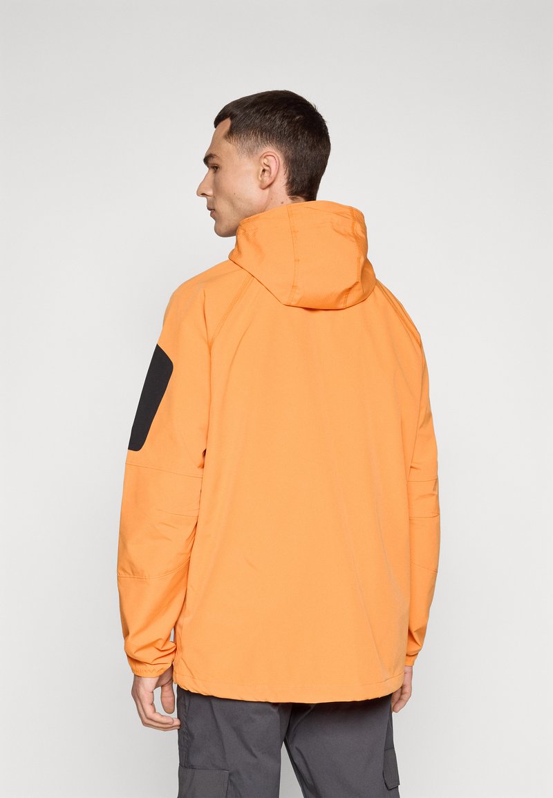 Pomarańczowa kurtka z kapturem o luźnym kroju, z czarnymi akcentami na ramionach oraz fakturowanym materiałem. Lekka konstrukcja dla wszechstronności.