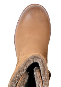 Beżowy skórzany but z zaokrąglonym noskiem, miękką wyściółką wewnętrzną i widocznym przeszyciem. Górna krawędź jest lekko zawinięta, odsłaniając puszyste, teksturowane wnętrze.