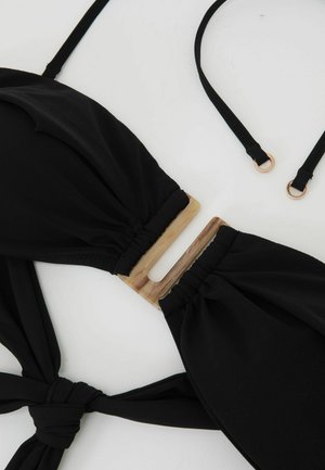 Must bikiinide ülaosa, millel on seotud rihmad ja beež ristkülikukujuline klamber detailiga valgel taustal.