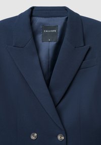 Blazer blu navy realizzato in tessuto strutturato, caratterizzato da un design doppiopetto, rever a punta e due bottoni con una fodera interna liscia.
