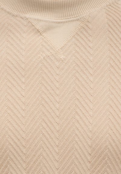 Φωτεινό μπεζ πλεκτό πουλόβερ με λαιμόκοψη σε σχήμα V και σχέδιο ψαροκόκκαλο. Η υφή είναι μαλακή και ριμπ γύρω από τη λαιμόκοψη.