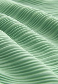 Tissu ondulé et texturé de couleur vert menthe doux, présentant des plis réguliers et une finition en maille lisse. Convient à diverses applications textiles.