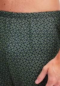 Zwarte en groene geblokte shorts met een zachte, elastische tailleband. De stof heeft met elkaar verbonden ronde ontwerpen, wat zorgt voor een gestructureerde uitstraling.