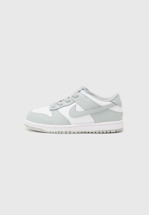 Low-Top Nike Sneaker in Weiß und Hellgrau mit Schnürsenkeln, mit dem Nike-Swoosh und einer strukturierten Sohle auf einfarbigem Hintergrund.