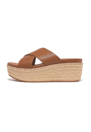 Brown leather platform sandals with crossed straps, featuring a woven jute sole and a thick, textured wedge base.