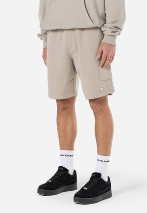 Beige shorts i bomullsblandning med en avslappnad passform, sidoficka och ton-i-ton logotypaccent. Kombineras med svarta sneakers och vita strumpor.