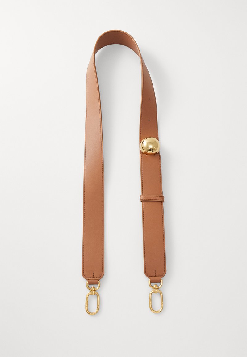 Correia de ombro em pele castanha com uma textura suave, apresentando um detalhe redondo dourado e clips de hardware dourado em ambas as extremidades.