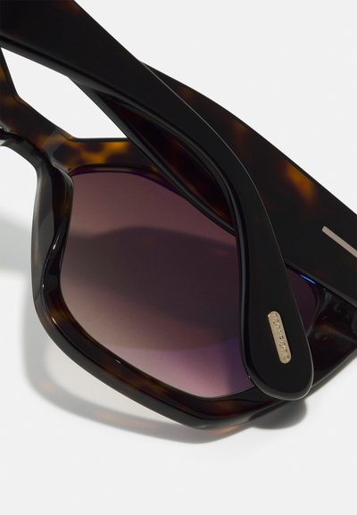 Tortoiseshell sunglasses with dark purple gradient lenses, chunky design, featuring gold-tone hardware and a sleek black arm.