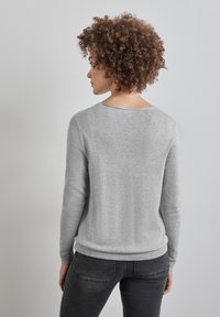 Ljusgrå tröja med långa ärmar, ribbade ärmslut och nederkant, samt rundad halsringning. Mjuk textur och minimalisk design.