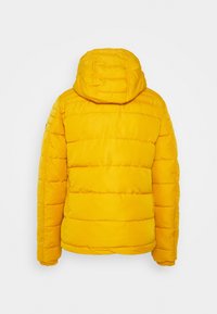 Žlutá prošívaná bunda s kapucí, s vodorovnými švy a hladkou texturou. Pohled zezadu ukazuje šití a přiléhavý střih.