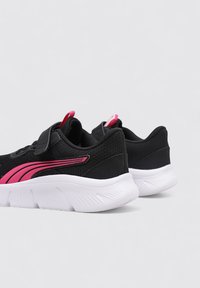 Baskets de sport noires avec des accents roses, dotées d'un dessus en mesh, d'une sangle réglable et d'une semelle intermédiaire blanche texturée.