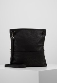 Borsa tote in pelle nera con superficie testurizzata, dotata di una tracolla lunga, dettagli in metallo argentato e design minimalista.