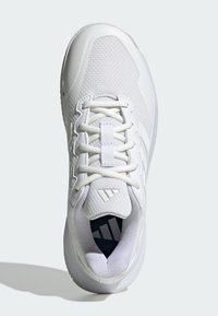 Biały but sportowy z siateczkową cholewką, teksturowanymi nakładkami, płaskimi sznurówkami i wyściełanym kołnierzem, z widocznym logo na języku.