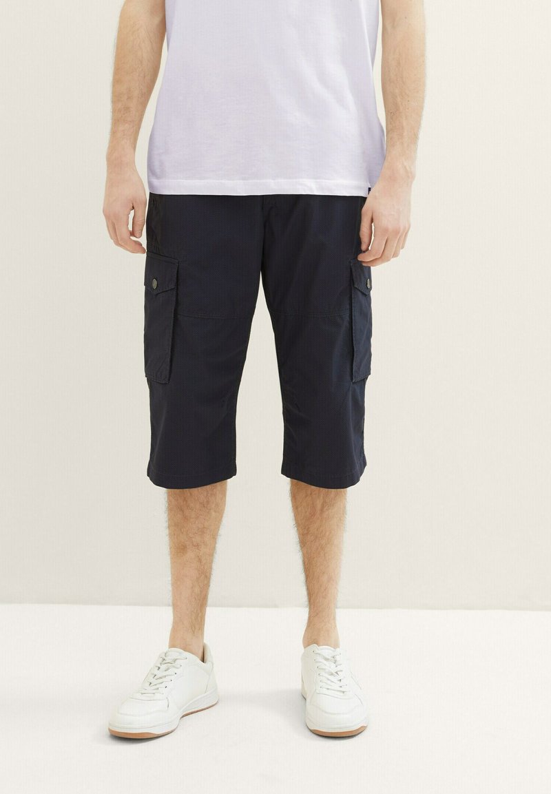 Navy Cargo-Shorts aus leichtem Stoff mit zwei Seitentaschen, regulärer Passform und knielangem Design, kombiniert mit weißen Sneakers.