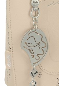 Beige Lederhandtasche mit perforierten Akzenten, ausgestattet mit einem silbernen Charme mit einem Durchbruchsdesign und einem gravierten "Liebe"-Tag.