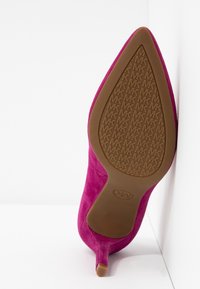 Escarpin rose en daim à bout pointu, montrant la semelle avec un motif répétitif du logo MK et un petit talon kitten.