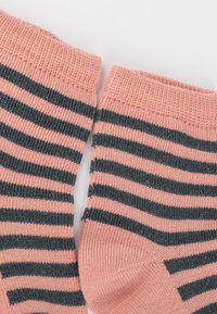 Rosa und graue gestreifte Socken nebeneinander auf einem weißen Hintergrund, die ihre gerippten Bündchen und die weiche Textur zeigen.