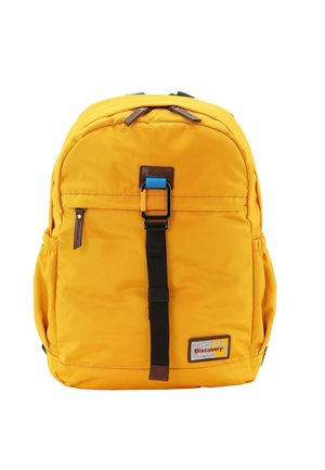 Mochila amarilla de nailon con forma redondeada, bolsillo frontal con cremallera, correa negra y acentos de cuero marrón. Presenta el logotipo de la marca en la parte inferior derecha.