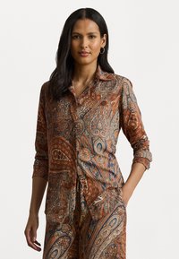 Button-up shirt made of soft fabric, featuring a paisley pattern in shades of brown, orange, blue, and cream, with roll-up sleeves.