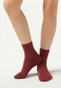 Calze in cotone bordeaux con una texture liscia, altezza alla caviglia, risvolti a coste e punta e tallone rinforzati per una maggiore durabilità.