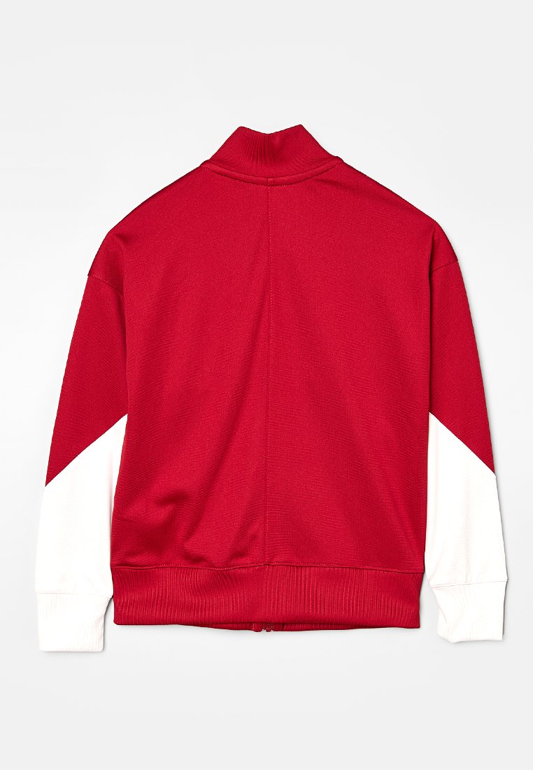 Veste zippée rouge avec un col haut, des poignets côtelés et des panneaux d'accent blancs sur les épaules. Le tissu semble doux et texturé.