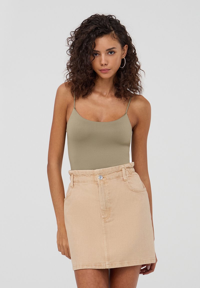 Body in verde oliva con spalline sottili abbinato a una mini gonna in denim beige chiaro con vita elastica e tasche laterali.