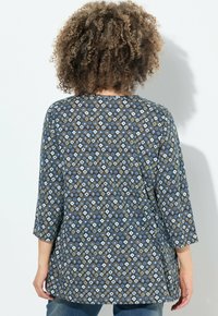Tunique blu con motivo a tre quarti; presenta forme geometriche in bianco e azzurro chiaro su uno sfondo scuro.