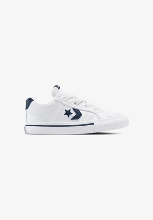 Baskets basses blanches avec un logo étoile et chevrons bleu marine, un patch talon bleu marine, des lacets blancs et une semelle en caoutchouc blanche avec une bande bleu marine.