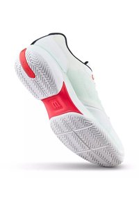 Chaussure de sport blanche inclinée montrant la semelle blanche texturée avec des accents rouges et le logo de la marque sur le talon et la semelle intermédiaire.