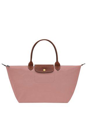 Pink tote bag with wide base, brown leather handles, and a small front flap pocket with a gold button closure.