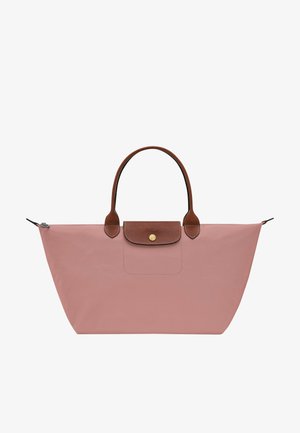 Pink tote bag with wide base, brown leather handles, and a small front flap pocket with a gold button closure.