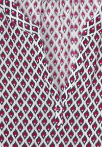 Top in cotone con sfondo bianco e motivo a rombi in rosso, rosa e nero, e un colletto a giro.