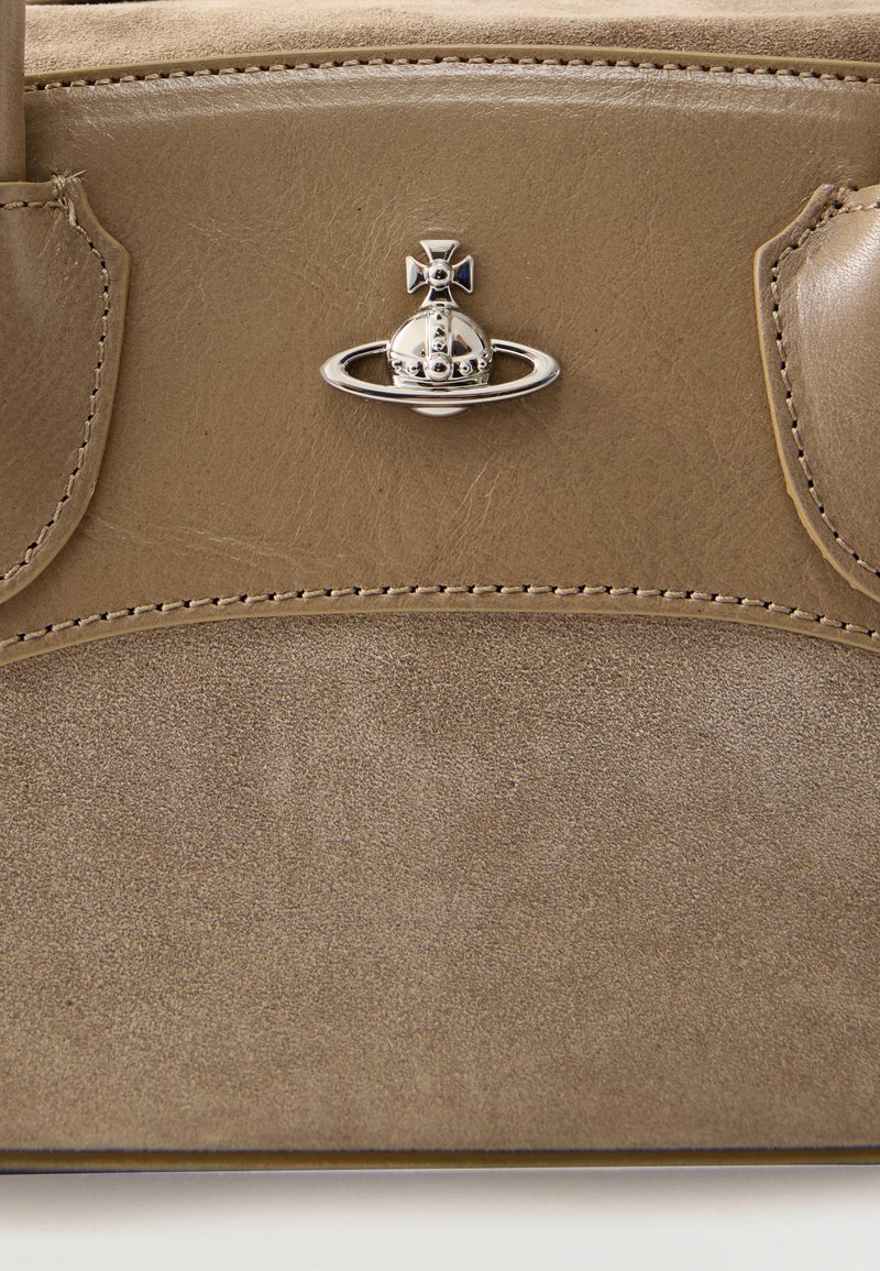 Brown leather and suede bag section with detailed stitching and a small silver orb emblem with a cross on top.