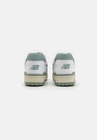 Białe sneakersy z zielonymi akcentami, wykonane z siateczki i skórki, w retro stylu, z teksturowanym obcasem, wyraźnym logo z tyłu oraz solidną gumową podeszwą.