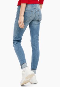 Ljust blå skinny jeans i denim, med en figursydd design, fem fickor och subtila blekningsdetaljer, i kombination med vita sneakers.