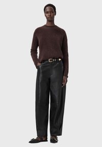 Brauner Mohair-Pullover, schwarze Lederhose mit weitem Bein, goldene Gürtelschnalle, minimalistisches Design, weiche Textur und flache schwarze Sandalen.