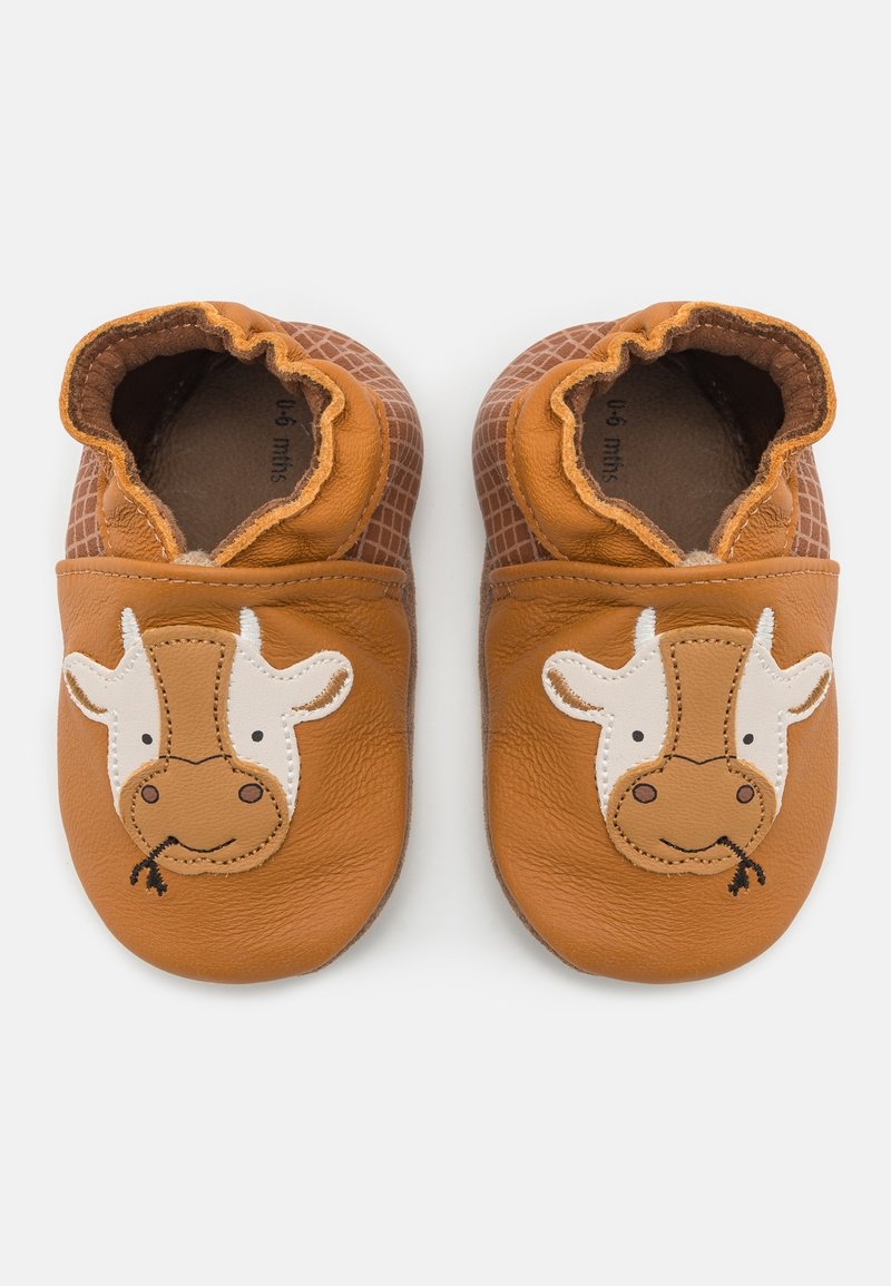 Skórzane buty dla niemowląt w kolorze brązowym z teksturowanym tyłem, z białym i brązowym wzorem w kształcie twarzy krowy, z elastycznym otwarciem ułatwiającym zakładanie.