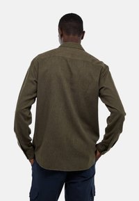 Chemise olive verte à manches longues, en tissu texturé, avec empiècement au dos et ourlet arrondi, dotée de poignets à boutons.