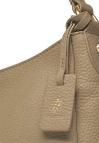 Beiger Lederhandtasche mit einer strukturierten Oberfläche, einem goldenen Logotag und einem dekorativen Knoten-Detail am Trageriemen.