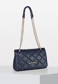 Navy blue quilted leather Valentino handbag with gold chain strap and logo, displayed on a white surface with plain background.