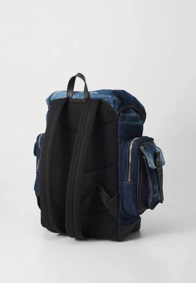 Rucsac din denim albastru cu panouri din plasă la spate, curele de umăr căptușite și buzunare laterale cu fermoar. Dispune de un mâner superior rezistent pentru o transportare ușoară.