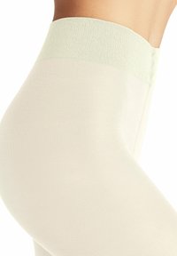 Collant beige chiaro con una morbida banda verde menta. Il tessuto è liscio e a costine, senza cuciture sui bordi, offrendo una vestibilità aderente.