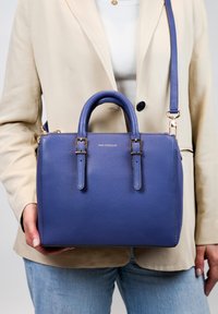 Blauwe lederen handtas met twee korte handvatten en een afneembare schouderriem. Bevat gouden hardware en een gestructureerde afwerking.