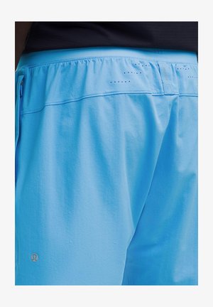 Close-up of a person wearing light blue athletic shorts with a black waistband and small ventilation holes near the top.