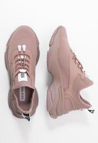 Scarpe da ginnastica rosa con una tomaia in maglia testurizzata, suola flessibile e un sistema di allacciatura distintivo. Presenta un colletto imbottito e un'etichetta del marchio sulla linguetta.