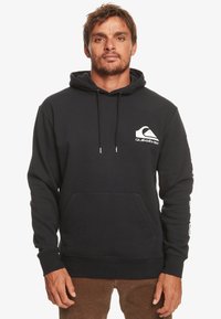 Felpa con cappuccio di un blu scuro, realizzata in un materiale misto cotone. Presenta una tasca a marsupio frontale, polsini a coste e il logo Quiksilver bianco sul petto e sulla manica.